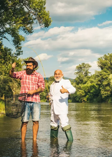 Pesce trota fario. Pescatore. Pescatore della mosca usando la canna da pesca della mosca nel fiume bello. Famiglia e generazione - vacanze estive e concetto di persone . — Foto Stock