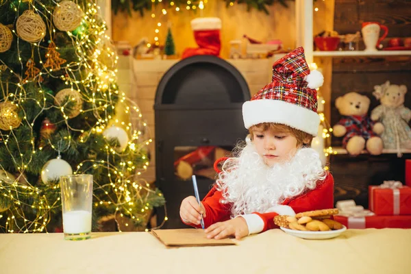 산타 클로스는 편지를 씁니다. 산타는 아이들의 편지를 읽는다. 산타 모자에 산타 소년. — 스톡 사진