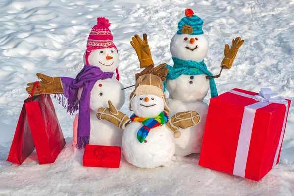 Feliz pareja de muñecos de nieve y niño muñeco de nieve con regalo de Navidad de pie en invierno paisaje de Navidad. Tarjeta de felicitación de Año Nuevo. Feliz Navidad y feliz año nuevo tarjeta de felicitación. —  Fotos de Stock