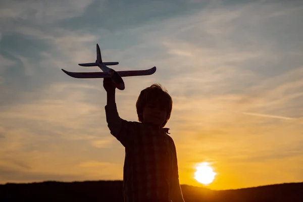 Little boy aviator over sunset. Little children with toy airplane in a field at sunset. Success and child leader concept. — Stock Photo, Image