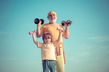Üst düzey adam ve sevimli çocuk halter kaldırma portresi. Sağlıklı yaşam ve spor konsepti. Vücut bakımı ve sağlık. Dedesi ve çocuk spor salonunda ağırlıkları ile çalışma.