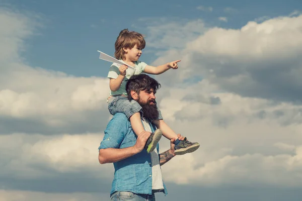 Baba ve oğul. Çocuk babasının omuzlarında oturuyor. Nesil. Mutlu çocuk kağıt uçak ile oynuyor. — Stok fotoğraf