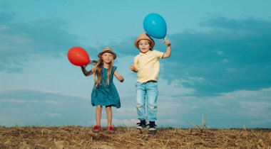 Çocuklar sonbaharda mavi gökyüzüne karşı eğleniyorlar. Mutlu çocukluk oynayan çocuk. Kırsal kesimde çocukluk. Çocukluk anıları. Çocuk bakımı.