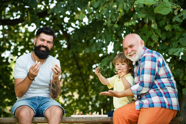 Nagyapja portré kék ég háttérrel. Boldog gyerekek időt. Boldog három generáció a férfiak szórakozni és játszani sakk a Green Park. — Stock Fotó