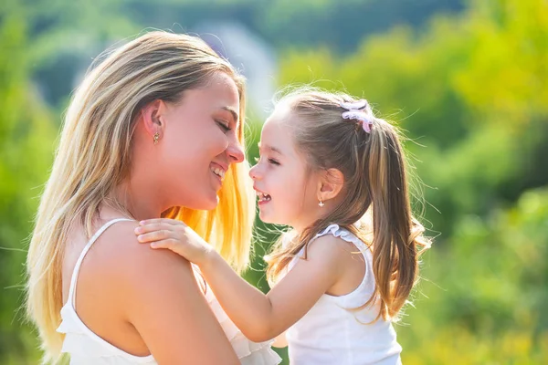 Amor infantil. La familia feliz y la mamá encantadora y la hija pasan el tiempo juntos - el día de las madres. Día de las madres. Madre e hija disfrutan y miran a la cámara. —  Fotos de Stock