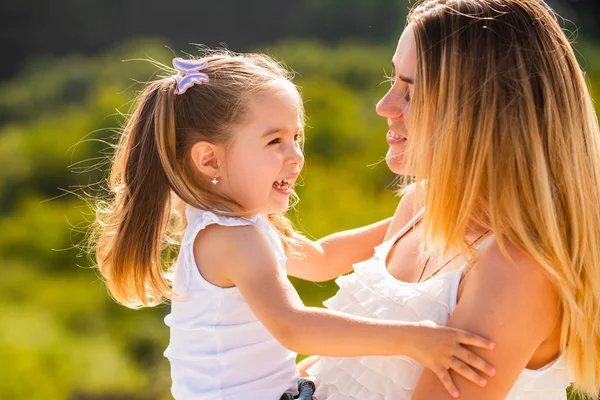 Mother love. Happy woman and little girl daughter smiling. Happy family mother and child daughter hugging and kissing. Lifestyle portrait mom and daughter in happy mood at the outside. — Stock Photo, Image