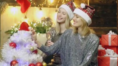 Mutlu noeller ve mutlu yıllar. İki sarışın kız ve Noel süsleri. Kız arkadaşları yeni yıl parti şampanya yeni yıl arka plan içme kutluyor. Mutlu insanlar. Gerçek Duygular.