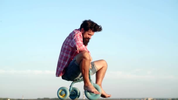 Pazzo uomo divertente va in bicicletta su sfondo cielo. Uomo divertente divertirsi in bicicletta per bambini. Hipster con la faccia buffa. Età diverse. Divertente pazzo . — Video Stock