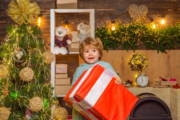 クリスマスの子供たち - 幸福の概念。小さなサンタクロースの贈り物。ホームクリスマスの雰囲気。クリスマスプレゼントを開く陽気なかわいい子供。クリスマスプレゼントを持つ幸せな子供. — ストック写真