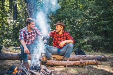 Kamp ateşinin yakınında kamp ta olan iki yakışıklı adam arkadaş. Arkadaşlar erkekler yürüyüşçüler kampta birlikte ateş izliyorlar. İki arkadaş eğlence hafta sonu yürüyüş piknik orman doğa arka plan harcamak.