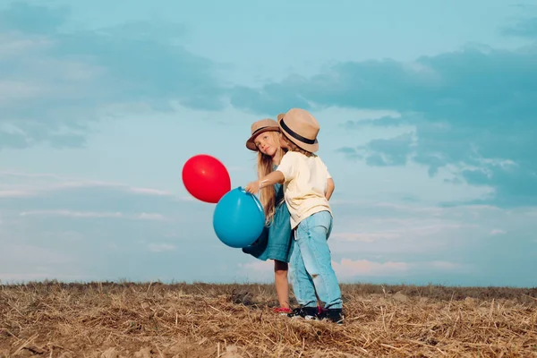 Kids birtoklás móka-ban mező ellen kék ég háttér. Szerelmi történet. Boldog gyermek lány és fiú ölelés a réten nyáron a természetben. Valentin-napi üdvözlőlap. — Stock Fotó