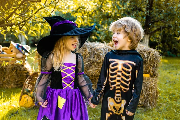 Cadılar Bayramı çocuk tatil konsepti. Cadılar Bayramı kostümleri giyen çocuklarla Cadılar Bayramı partisi. Iskelet ve cadı kostümü tutan ve şeker yeme ile Mutlu çocuklar. Trick-or-treat çocuk kavramı. — Stok fotoğraf