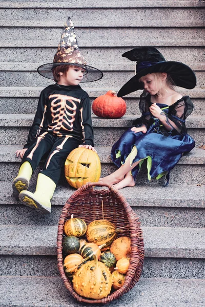Gyermek húga és testvére, sütőtök öltözött, mint a csontváz és a boszorkány a Halloween Party. Halloween portréja boldog aranyos gyermek. — Stock Fotó