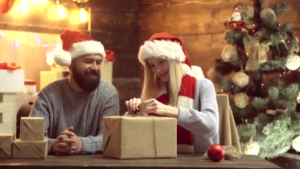 Ένα ζευγάρι εκπλήσσει με ένα χριστουγεννιάτικο δώρο. Νέο έτος αστείο ζευγάρι. Αρχική Χριστουγεννιάτικη ατμόσφαιρα. — Αρχείο Βίντεο