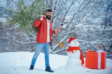 Adam bir Noel ağacı kesecek. Kış hissi. Ormanda noel ağacını yeni kesilmiş sakallı adam. Mutlu kış zamanı. Mutlu Noeller ve Mutlu Tatiller.