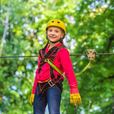 Küçük kız yüksek halat parkına tırmanıyor. Roping Parkı. Halat parkı. Küçük çocuk çocukluk yıllarını sever. Denge kiriş ve halat köprüler. Oyun alanında oynayan küçük kız.