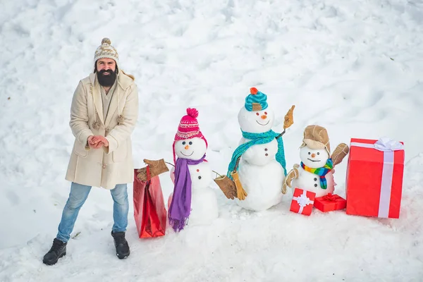 Mann mit rotem Geschenk spielt mit Schneemann im Winterpark. Wintergefühle. Winterurlaub und Personenkonzept. Frohe Weihnachten und frohe Feiertage. — Stockfoto