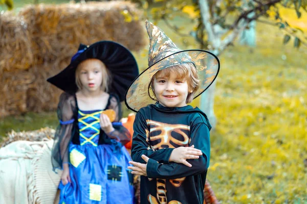 Twee kinderen zoals skelet of heks klaar voor truc of traktatie. Verrast groep kleine zombie in Halloween kostuum eten traktatie, calaverita snoep kaarsen. — Stockfoto