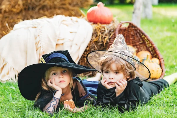 Összetétele sütőtök és Halloween dekoráció a gyermekek a kertben. Halloween jelenet aranyos gyerekek. — Stock Fotó
