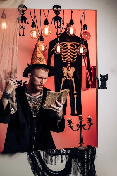 Hombre de Halloween con sonrisa sobre fondo oscuro. Magia, encantamiento, brujería. Hombre de Halloween con calabaza en la oscuridad. Divertido mago sabio en un fondo de Halloween . —  Fotos de Stock