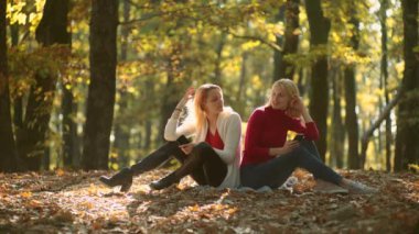 Sonbahar doğal arka plan üzerinde gülümseyen kızlar. Sonbahar parkında oynuyorum. Sonbahar parkında iki kız. Telefonu olan kızlar. Akıllı telefon kullanan iki kız.