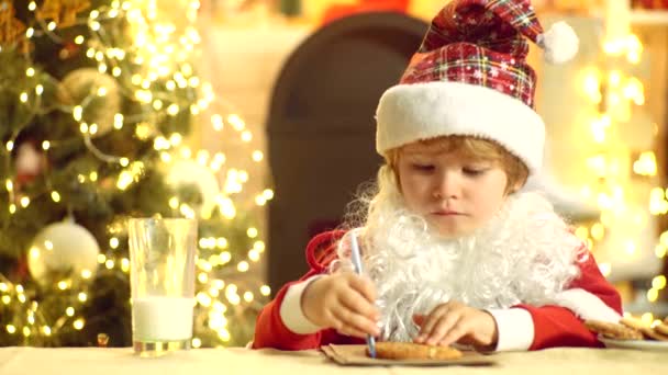 Portrait of little Santa child holding chocolate cookie. Santa Claus - bearded funny child. Santa in home. Christmas for kid. Happy Santa Claus - little child boy with cookie. — Stock Video