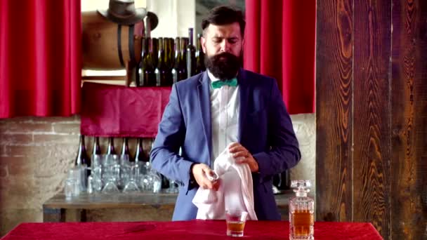 Il barman tiene un bicchiere di whisky. Elegante elegante barbuto Barista tiene bicchiere di whisky. Bevanda alcolica di lusso . — Video Stock