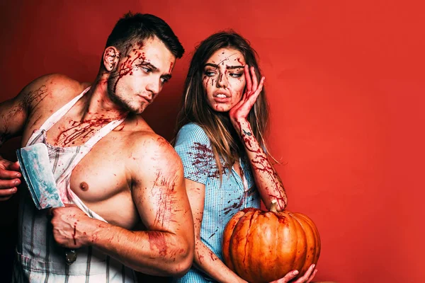Halloween student party in blood. Couple of muscular man and bloody young woman with wounds and red blood. Terrifying zombie couple.