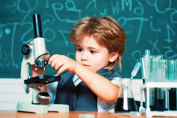 Tudományos és oktatási koncepció. Kémia tudomány. Általános iskola. Iskolás. Vidám mosolygós kisfiú szórakozás a kék fal ellen. — Stock Fotó