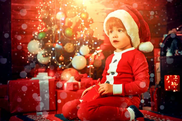 Śliczne dziecko otwierające prezent świąteczny. Piękne dziecko cieszyć się Boże Narodzenie. Santa chłopiec małe dziecko zimą świętować w domu. Chłopiec Cute dziecko wesoły nastrój grać w pobliżu choinki. Wesołych i jasnych świąt Bożego Narodzenia — Zdjęcie stockowe