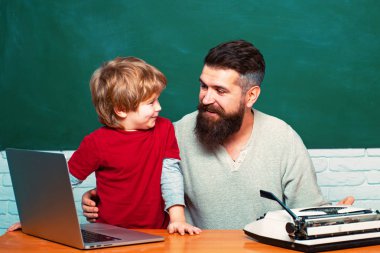 Okula geri ve eğitim konsepti. Sınıfta ilkokul öğretmeni ve öğrencisi. Boşluk Kopyala. Öğretmenler sınıfta masalarda okuyan öğrencilere yardımcı olur. Baba öğretmen.