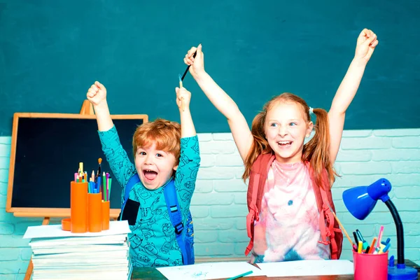 Torniamo a scuola. Bambino delle elementari con libro e borsa. I bambini si preparano per la scuola. Bambino amichevole in classe vicino alla scrivania della lavagna . — Foto Stock