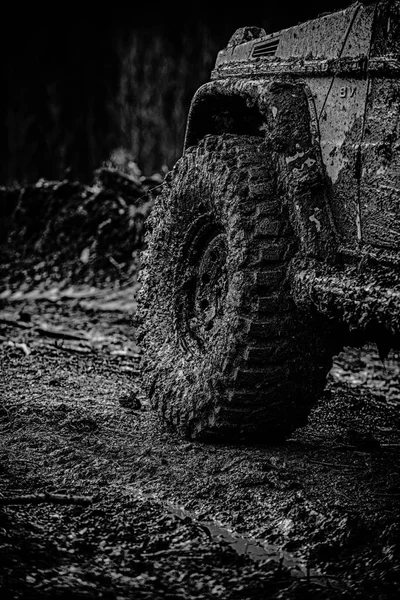 Off road sport truck mezi hory krajina. Mudding je v terénu prostřednictvím oblast vlhkého bláta nebo jílu. Pohled zdola na velké terénní auto kola na zemi silnici a hory pozadí. — Stock fotografie