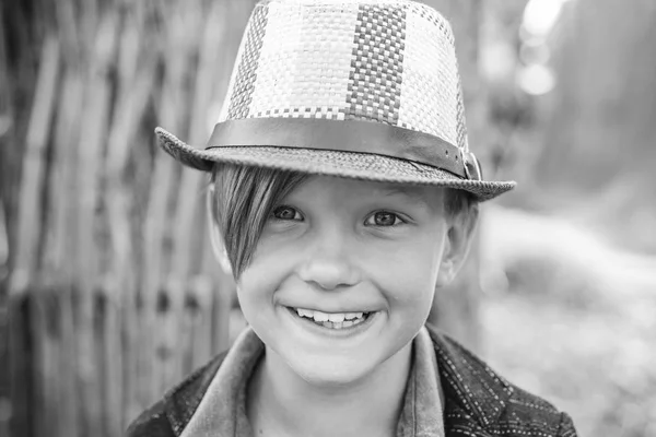 Glimlachend jongetje dat met bladeren speelt en naar de camera kijkt. Close-up portret. Schattig jongetje. — Stockfoto