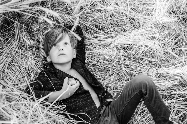 Kid boy holding gold leaf and lies on the hay. Sale for entire autumn collection, incredible discounts and wonderful choice. Back to school. Bye summer - hi autumn.