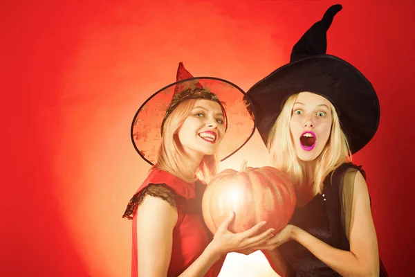 Dos mujeres jóvenes emocionales en disfraces de Halloween en fiesta con calabaza. Las mejores amigas celebran el día de acción de gracias. riendo divertido hermana gemelos niñas en brujas trajes en halloween . —  Fotos de Stock