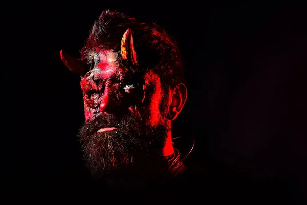 Happy Halloween - handsome Demon isolated on dark background. Devil man with bloody eyes. Design for Halloween banner. Halloween bearded man with blood make-up.
