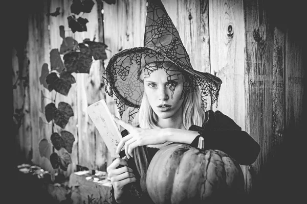Cadı kız balkabağına ahşap arka plan üzerinde kesmek hazırlanıyor. Cadılar Bayramı kavramı. Yakın çekim portre muhteşem sarışın peri. — Stok fotoğraf