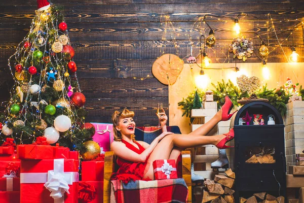 Mutlu Noeller dilerim. Şaşırmış kadın. Sarışın ve kırmızı dudaklı güzel kız bir hediye kutusu tutuyor. Eski moda saç stili ve Noel ağacının üstünde makyaj yapan genç bir kız.. — Stok fotoğraf