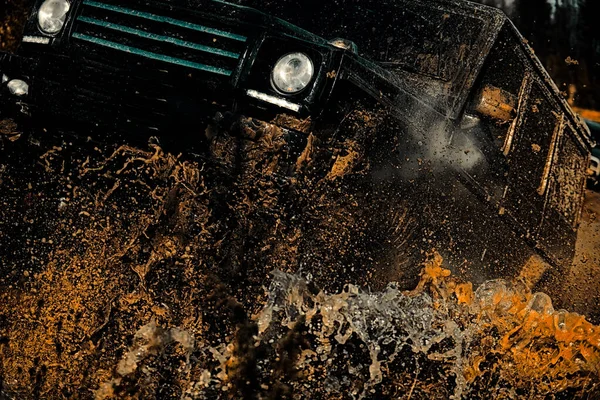 Neumáticos en preparación para la carrera. Jeep chocó contra un charco y recogió un chorro de tierra. Salpicaduras de barro y agua en las carreras off-road . — Foto de Stock