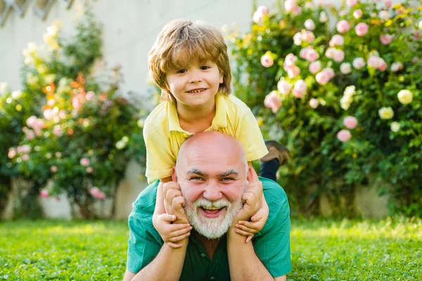 Cute boy with dad playing outdoor. Happy family Grandson hugs his grandpa on holiday. Happy grandfather and grandson relaxing together. Concept of friendly family. — Stock Photo, Image