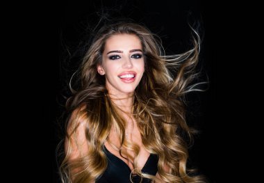 Stüdyo moda çekimi. Güzel, neşeli ve eğlenceli bir kadın. Sarışın, kıvırcık saçlı, siyah arka planda gülümseyen bir kadın..