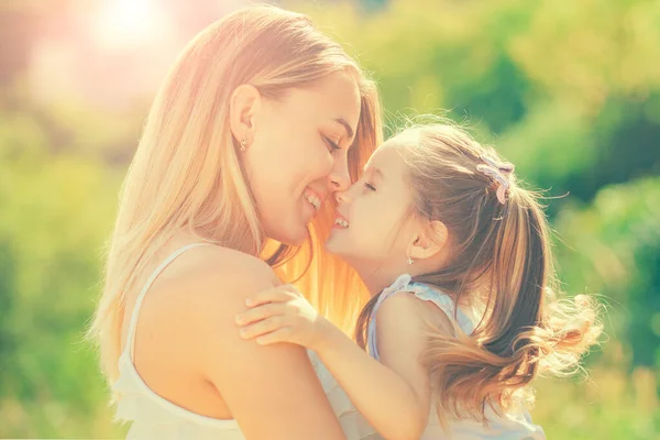 Kinderliebe. Glücklich lächelnde Mutter mit ihrer kleinen Tochter vor dem Hintergrund des Sonnenuntergangs. glückliche Mutter umarmt ihre Tochter. — Stockfoto