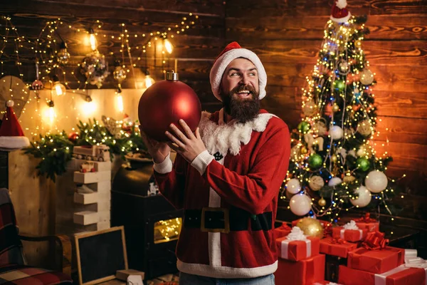 Portrait of happy Santa with decorative toy balls near Christmas tree. — Stock Photo, Image