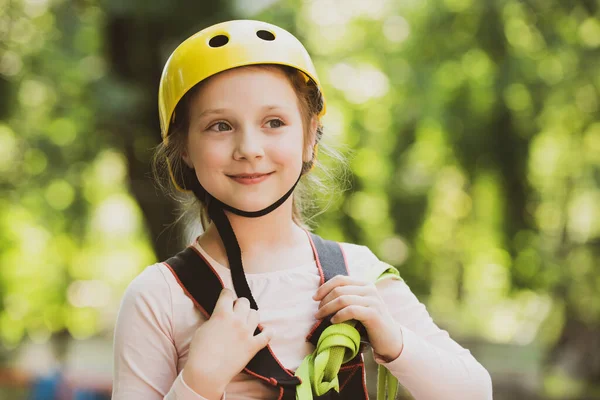 Bergsteigerin kleines Mädchen beim Training. Nettes Schulmädchen genießt einen sonnigen Tag in einem Klettererlebnispark. Kleines Mädchen hat Spaß im Abenteuerpark. — Stockfoto