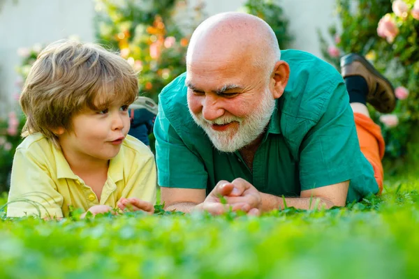 Avô e neto felizes relaxando juntos. Dia dos pais. Rapaz bonito com o pai a brincar ao ar livre. Duas gerações diferentes idades: avô e neto juntos. — Fotografia de Stock