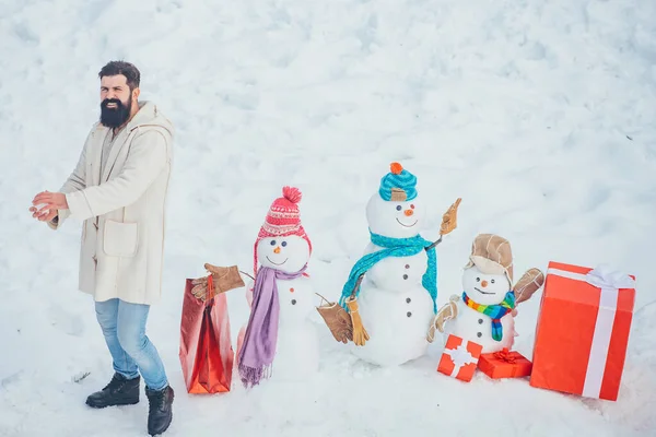 Feliz Navidad y Feliz Año Nuevo. Preparación de Navidad - hombre barbudo divertido con caja de regalo roja hacer muñeco de nieve . — Foto de Stock