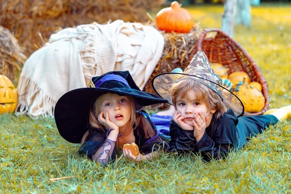 Halloween kinderfeest in de tuin met pompoenen. Jack-o-lantaarn. Leuke kinderen dochter en zoon die grappige gezichten trekken met een pompoen. Gelukkige Halloween. — Stockfoto