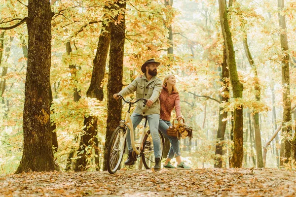 Joyful marriage couple having a picnic in the park, cycling a bicycle. Real love. Beautiful young couple bonding and smiling.