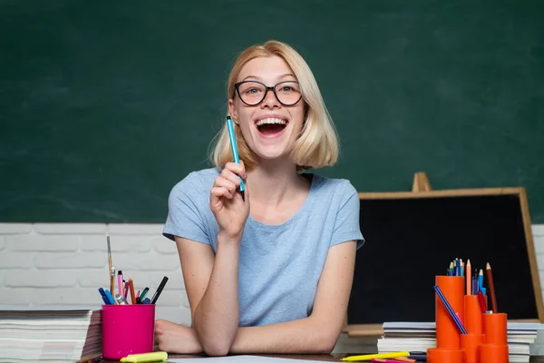 Πορτρέτο μιας φοιτήτριας στο πανεπιστήμιο. Φοιτητής και διδασκαλία έννοια της εκπαίδευσης. Αστεία νεαρή δασκάλα στην τάξη. Νεαρός δάσκαλος σε γυαλιά πάνω από πράσινο φόντο πίνακα. — Φωτογραφία Αρχείου